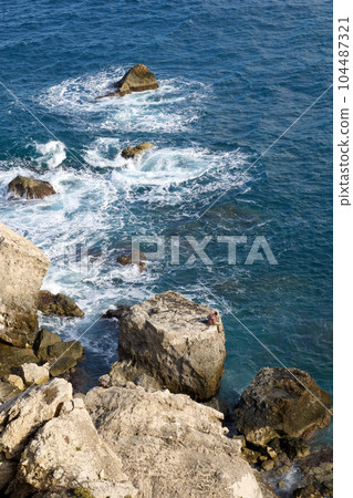 MELLIEHA, MALTA - JANUARY 01, 2020: Rocky coastline with heavy surf on the northeast coast of the island of Malta near the Coral Lagoon 104487321