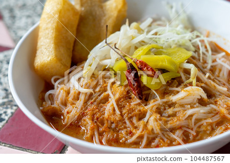 Rice noodles in fish curry sauce with vegetables  104487567