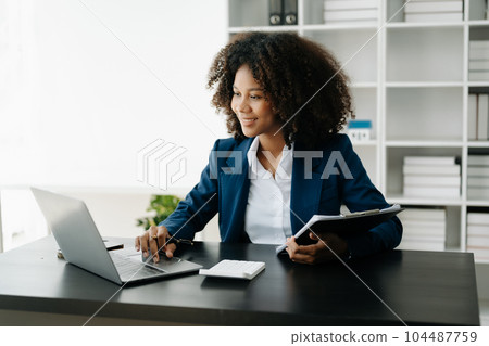 African Woman freelancer is working her job on computer tablet and laptop Doing accounting analysis report real estate investment data, Financial at office 104487759
