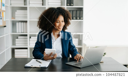 African Woman freelancer is working her job on computer tablet and laptop Doing accounting analysis report real estate investment data, Financial at office 104487821
