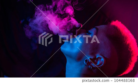 Close up portrait of asian woman with short hair smoking in neon light.  104488168