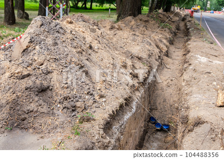 Earthworks, trench digging. A long earthen trench is dug for laying pipes. Repair in the city. 104488356