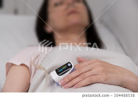pulse oximeter on the finger close-up. patient in the hospital on a bed. pulse oximeter on the finger close-up. patient in the hospital on a bed. 104488538