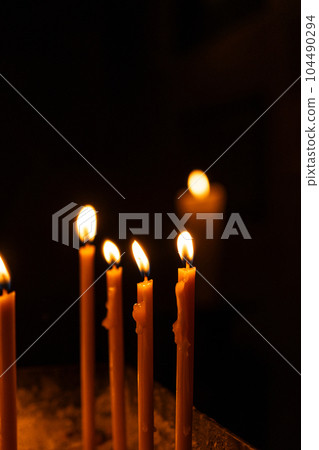 A lot of burning candles in the temple in the dark. The concept of religion, prayer and God. 104490294