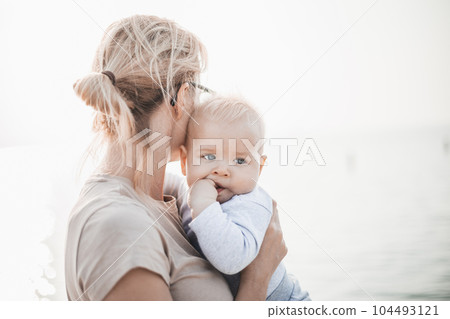 Tender woman caressing her little baby boy infant child outdoors. Mother's unconditional love for her child. Tender woman caressing her little baby boy infant child outdoors. Mother's unconditional love for her child. 104493121