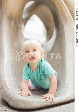 Child playing on outdoor playground. Toddler plays on school or kindergarten yard. Active kid on stone sculpured slide. Healthy summer activity for children. Little boy climbing outdoors 104493126