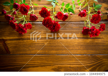 bouquet of red small roses, on a wooden background. 104494975