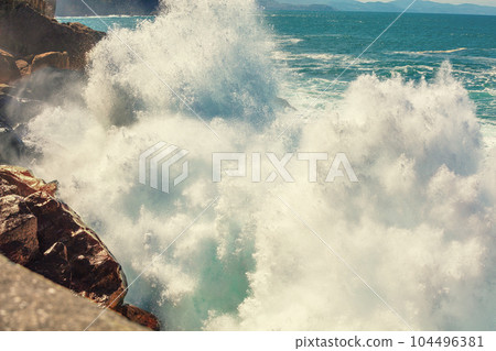 A huge wave is breaking on the rocks. Splash of the wave. Rocky seashore. Beautiful nature, landscape, stormy sea. San Sebastian, Basque Country, Spain, Europe 104496381