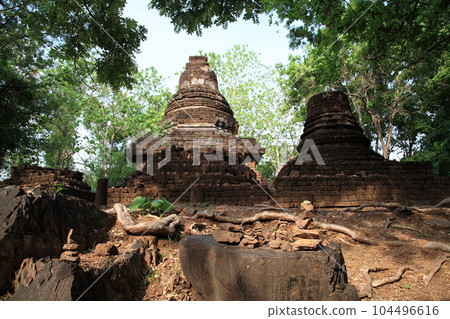 Stack rocks and banyan tree root with brick pagoda in Sukhothai 104496616