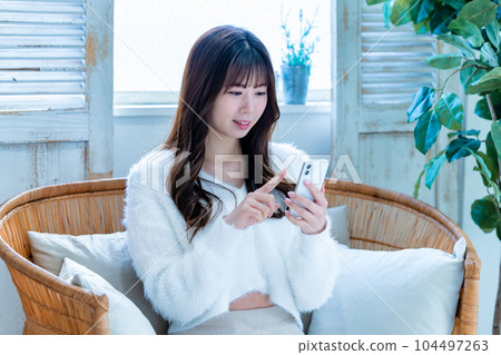 Young woman using a smartphone on the sofa Young woman using a smartphone on the sofa 104497263