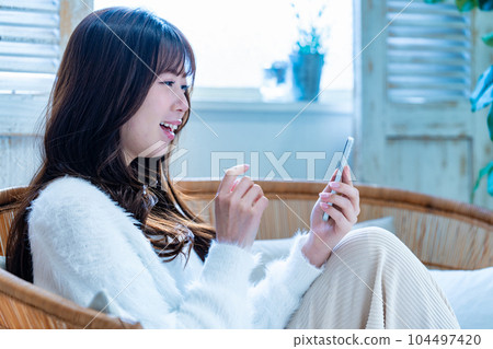 Young woman using a smartphone on the sofa 104497420