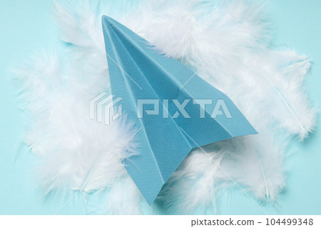 Paper plane and feathers on blue background Paper plane and feathers on blue background 104499348