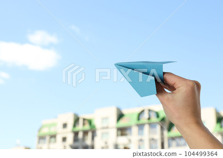 Female hand with paper plane on sky background 104499364