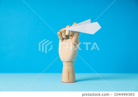 Wooden hand with paper plane on blue background Wooden hand with paper plane on blue background 104499365