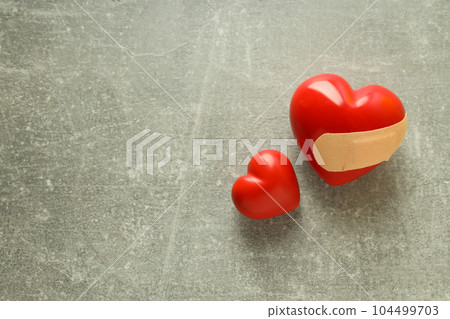 Red hearts and adhesive plaster on gray textured background 104499703