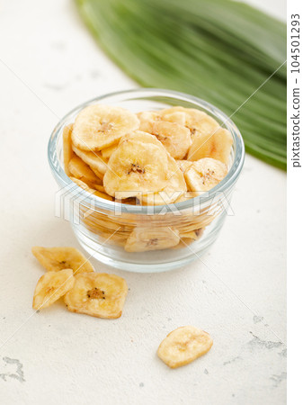 Dried banana chips snack in glass bowl plate on light board. Dried banana chips snack in glass bowl plate on light board. 104501293