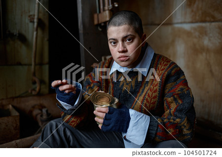 Hungry homeless castoff young woman eating canned food 104501724