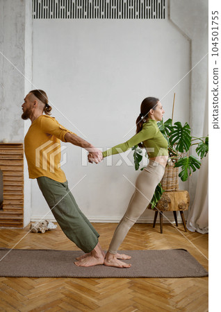 A couple training yoga in pair doing acrobatic plank together A couple training yoga in pair doing acrobatic plank together 104501755
