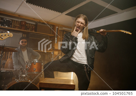 Excited expressive rock guitarist gesturing fist with rock-and-roll devil sign 104501765