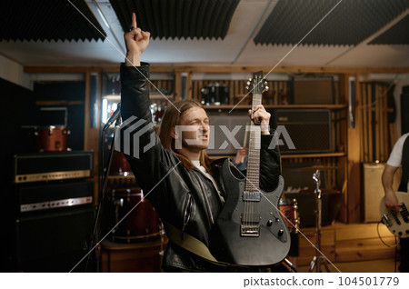 Portrait of expressive rocker playing last chord of song on his guitar 104501779