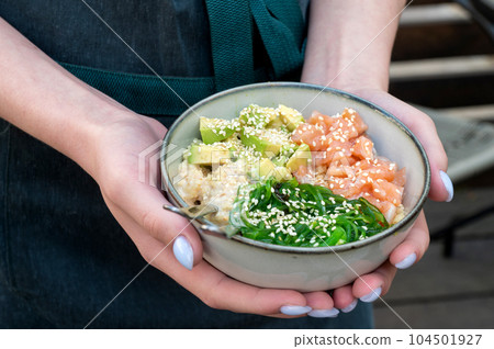 A woman holds a traditional Hawaiian couscous with fish in her hands. Hawaiian and Japanese cuisine. A woman holds a traditional Hawaiian couscous with fish in her hands. Hawaiian and Japanese cuisine. 104501927