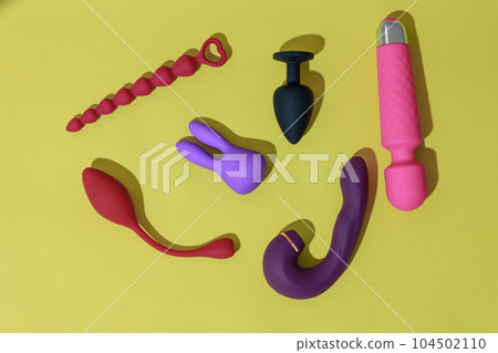 Top view of adult sex toys such as dildo, vibrator, buttplug on yellow background. Sex shop concept 104502110