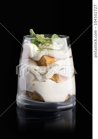 tiramisu cake with with mint on a black background with reflection. menu restaurant tiramisu cake with with mint on a black background with reflection. menu restaurant 104502727