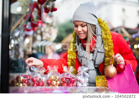 Happy girl chooses Christmas toys on the street market Happy girl chooses Christmas toys on the street market 104502872