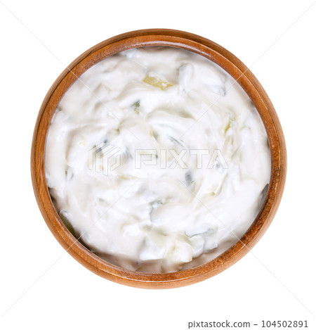 Tzatziki, in a wooden bowl. Fresh Greek dip sauce, served as an appetizer (meze) or side dish, and made of strained yogurt, mixed with cucumber, garlic, salt, olive oil and with dill, mint or parsley. 104502891