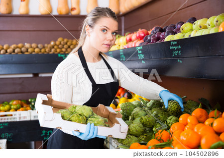 Woman seller lays out fresh fruits of the box on the grocery store Woman seller lays out fresh fruits of the box on the grocery store 104502896