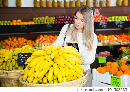Young female choosing fresh bananas on the supermarket 104502985