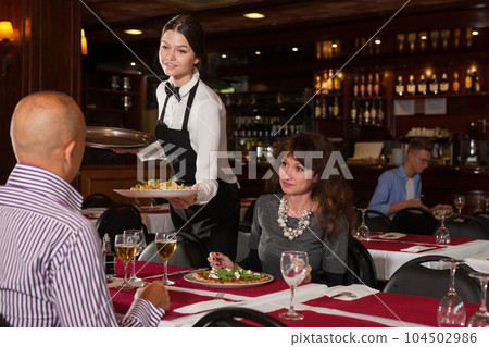 Waitress bringing ordered dishes to couple 104502986