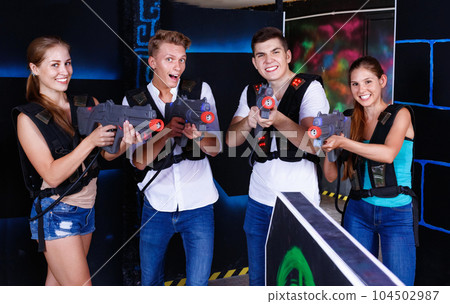 Group portrait of joyful young people with laser guns in their h 104502987