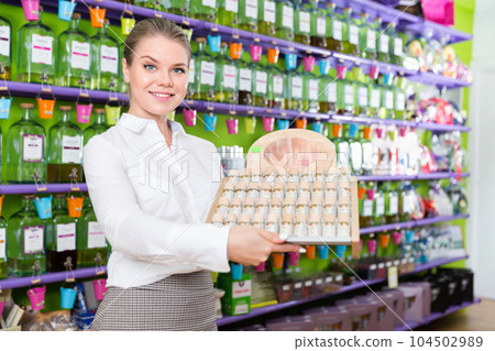 Positive salesgirl suggesting perfume in modern cosmetic store 104502989