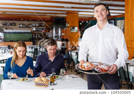 Waiter demonstrating tray of lobsters 104503005