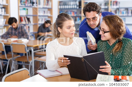 Female students working with professor in library Female students working with professor in library 104503007