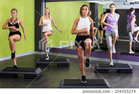 Women doing step aerobics exercises Women doing step aerobics exercises 104503274