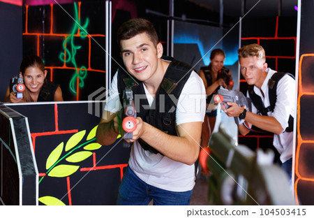 Portrait of excited guy with laser pistol playing laser tag in a Portrait of excited guy with laser pistol playing laser tag in a 104503415