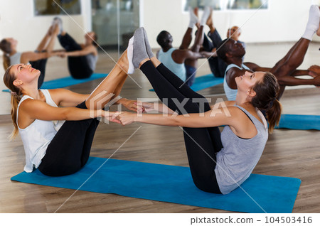 females and males doing stretching workout in pairs females and males doing stretching workout in pairs 104503416
