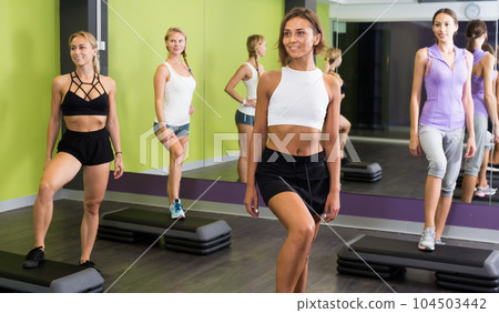 Smiling athletic girls performing step aerobics Smiling athletic girls performing step aerobics 104503442