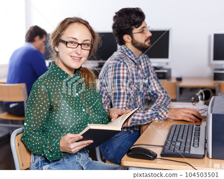 Female student reading textbook in computer class 104503501