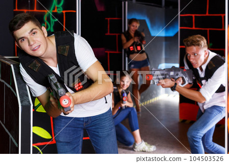 men and women playing emotionally laser tag game in arena men and women playing emotionally laser tag game in arena 104503526