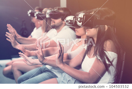 Female is enjoying exciting movie with friends in VR glasses Female is enjoying exciting movie with friends in VR glasses 104503532