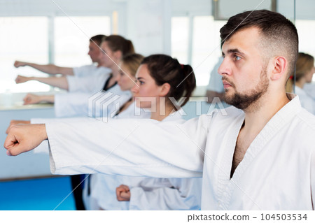 Adults trying new martial moves at karate class 104503534