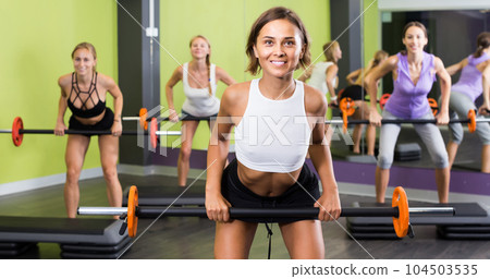 athletic girls during workout in gym with barbell athletic girls during workout in gym with barbell 104503535
