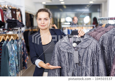 Shop assistant demonstrating coat in shop Shop assistant demonstrating coat in shop 104503537