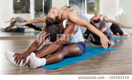 People doing stretching exercises in pairs People doing stretching exercises in pairs 104503539