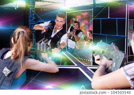 Two laser tag teams playing enthusiastically and aiming at each Two laser tag teams playing enthusiastically and aiming at each 104503540