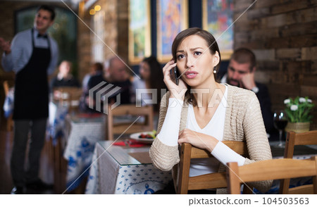 sad female in restaurant talking mobile phone sad female in restaurant talking mobile phone 104503563