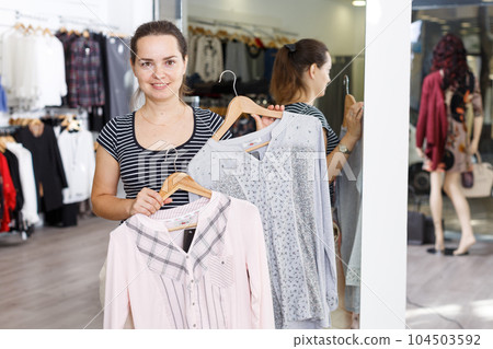 Woman holding and showing blouse on hanger Woman holding and showing blouse on hanger 104503592